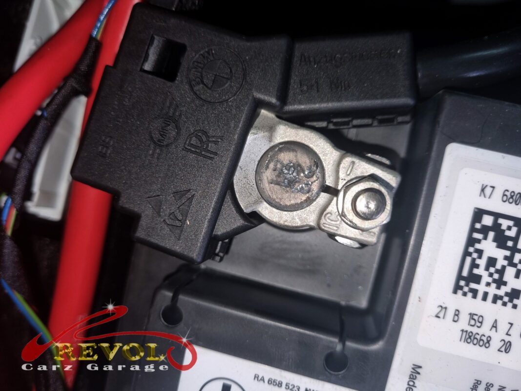 The battery negative terminal, the post crusted with corrosion, the battery nearing the end of its life.