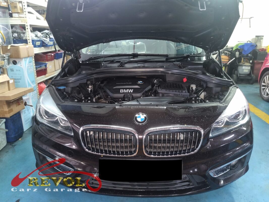 BMW 216d with the engine cover off and the timing pulley exposed for replacement.