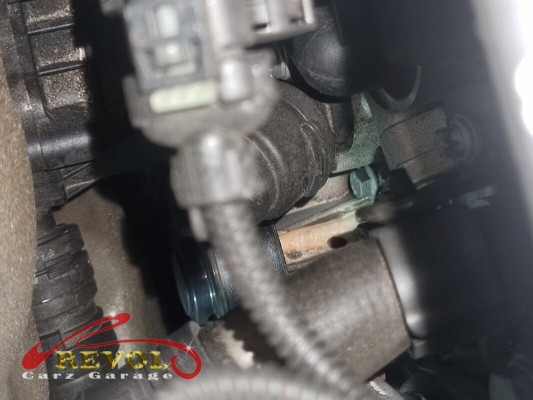 Coolant residue crusted around the connections at the front of the engine, the leak made visible.