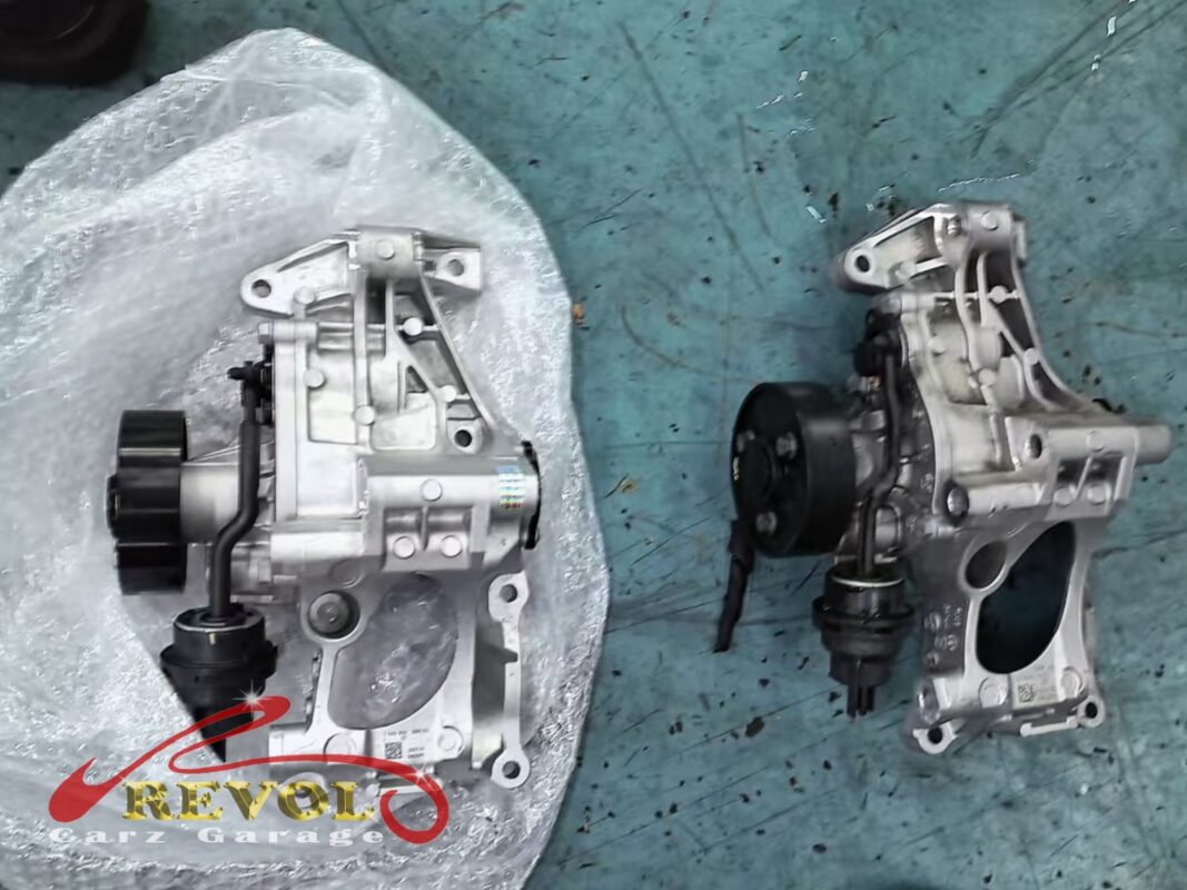 The old water pump and cracked housing (right, grimy) beside the new BMW-spec module (left).