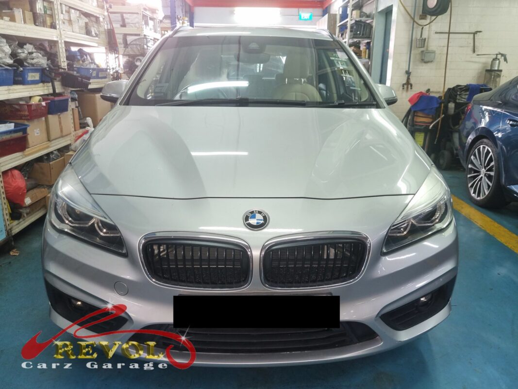 BMW 218i on the workshop lift with the front bumper open for radiator replacement.