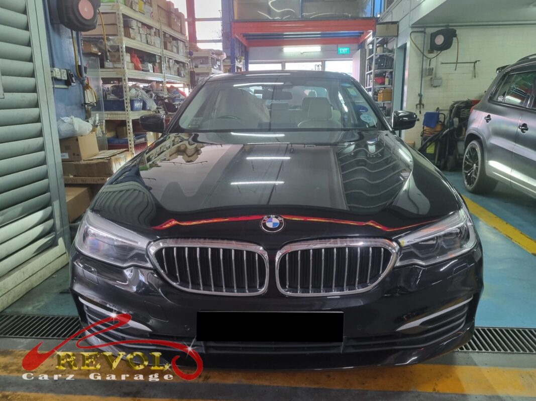 BMW 530i on the workshop lift with both front wheels off for control arm replacement.
