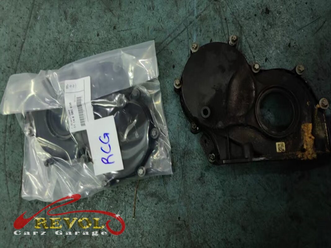 The old oil-stained timing cover (right) beside the new BMW-spec replacement (left).