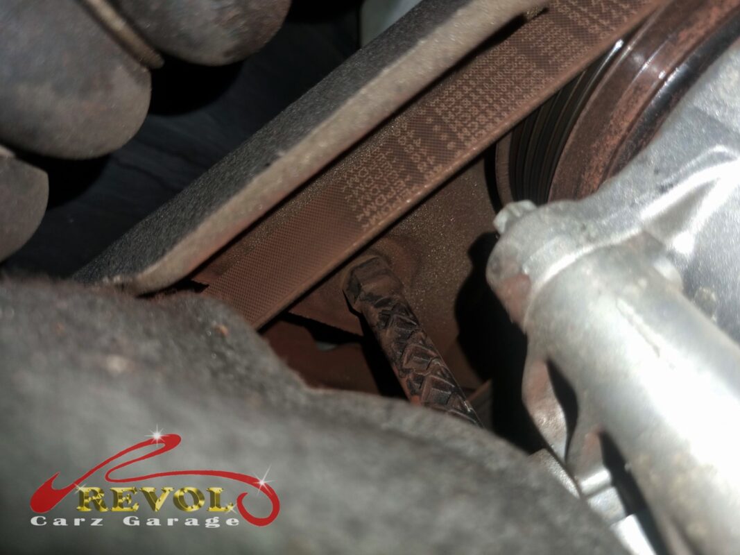 The worn accessory belt on the crankshaft pulley at the front of the engine.