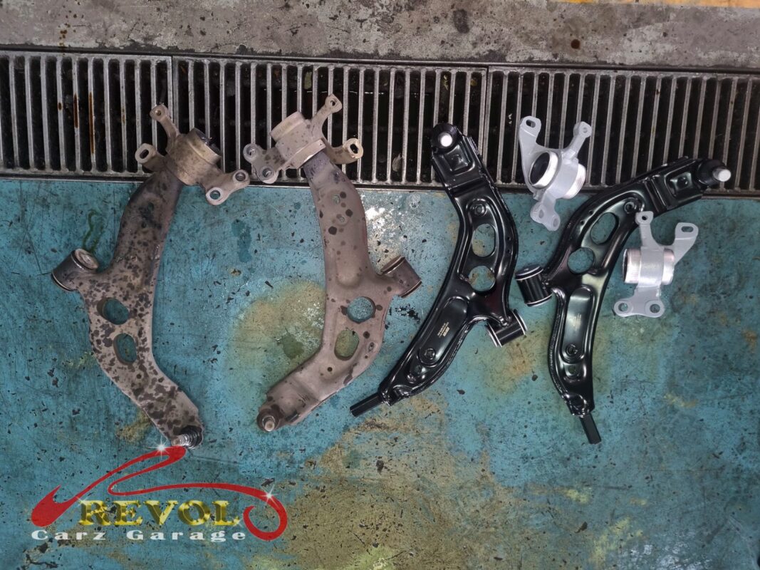 The two badly corroded old lower control arms (left) beside the new BMW-spec replacements with their fresh bushes (right).
