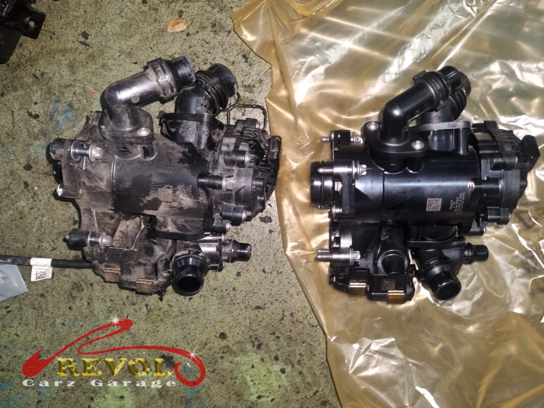 The old thermostat housing module (left, grimy) beside the new BMW-spec replacement (right).