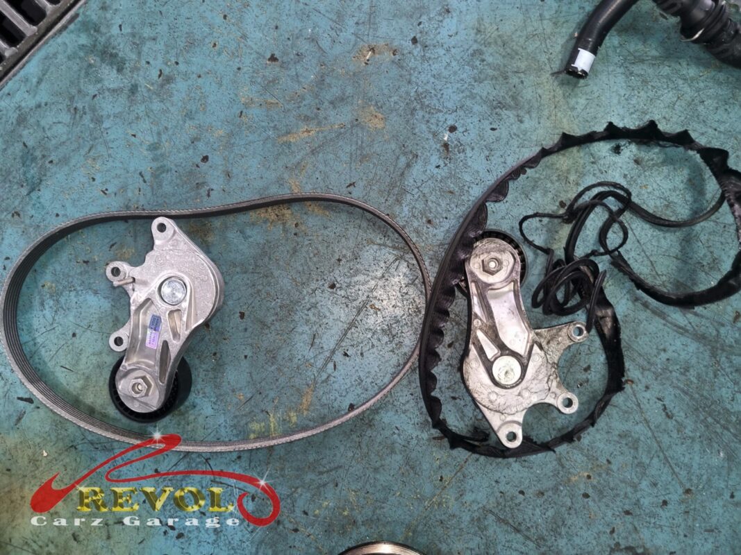 The new BMW-spec belt and tensioner (left) beside the old shredded belt and worn tensioner (right).