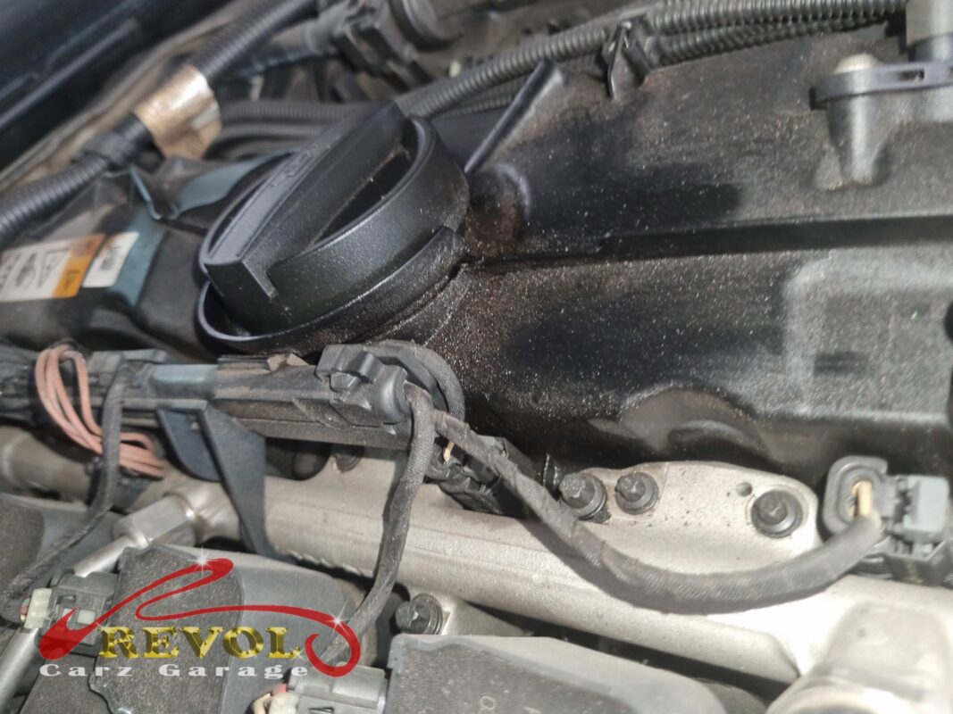 The valve cover caked in oily dust, the gasket weeping along the edge.