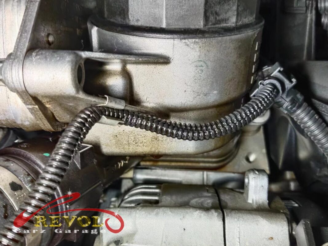 The oil filter housing on the engine, oil traces tracking down from the gasket.