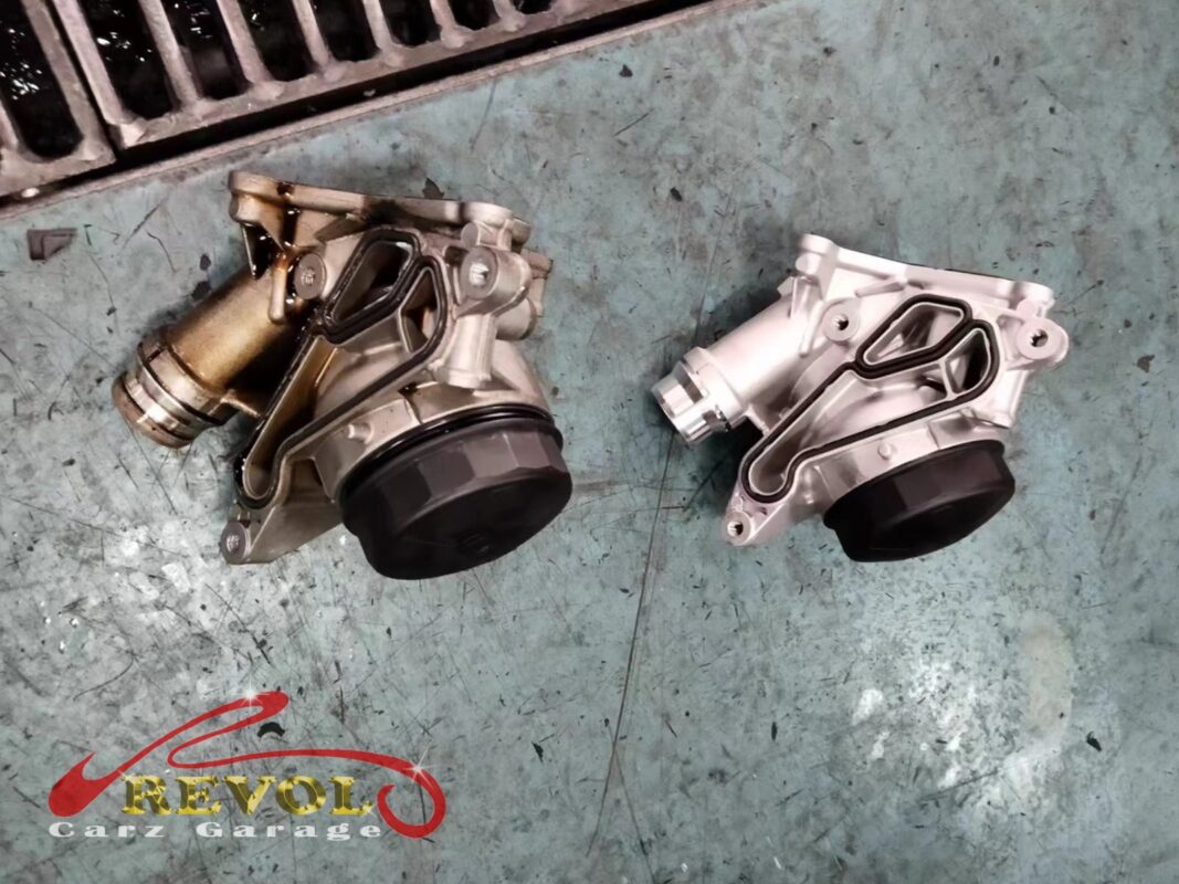 The old oil filter housing module (left, grimy) beside the new BMW-spec replacement (right).