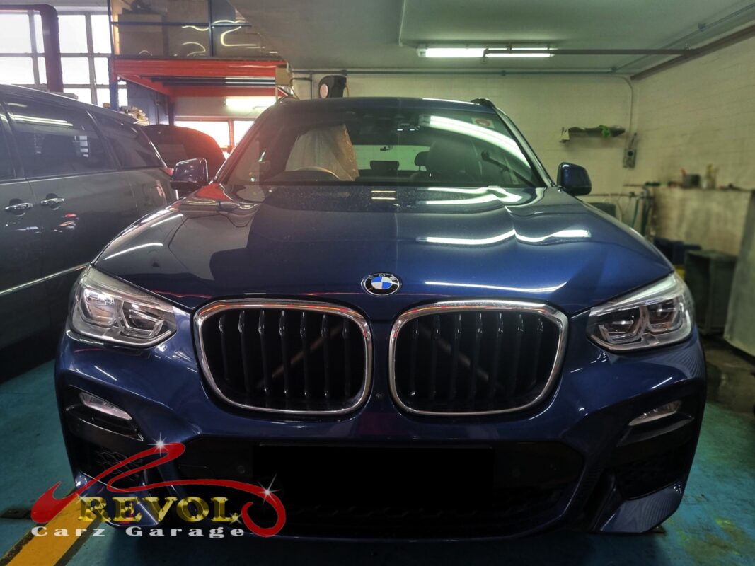 BMW X3 on the workshop lift with the front bumper open for radiator replacement.