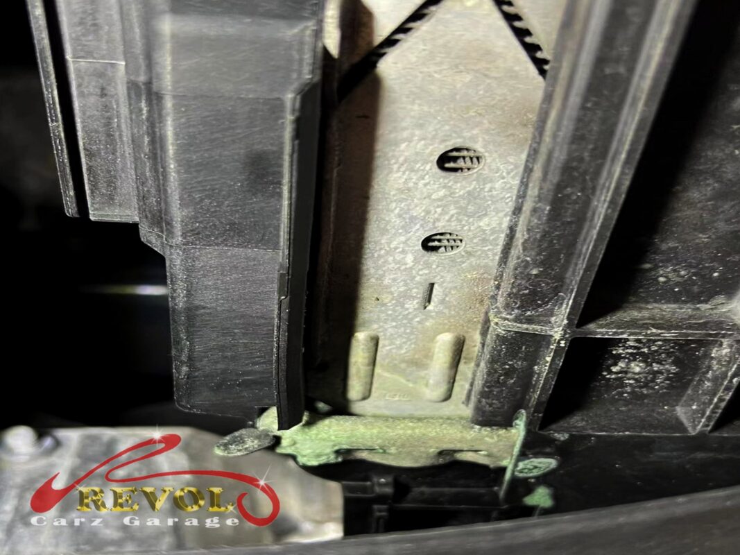 Green coolant residue crusted at the seam of the radiator's plastic end tank, the crack made visible.
