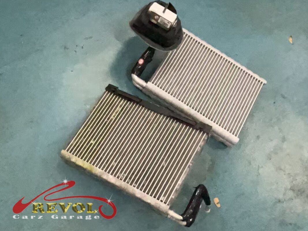 The old evaporator core (bottom, stained) beside the new BMW-spec replacement with its expansion valve (top).