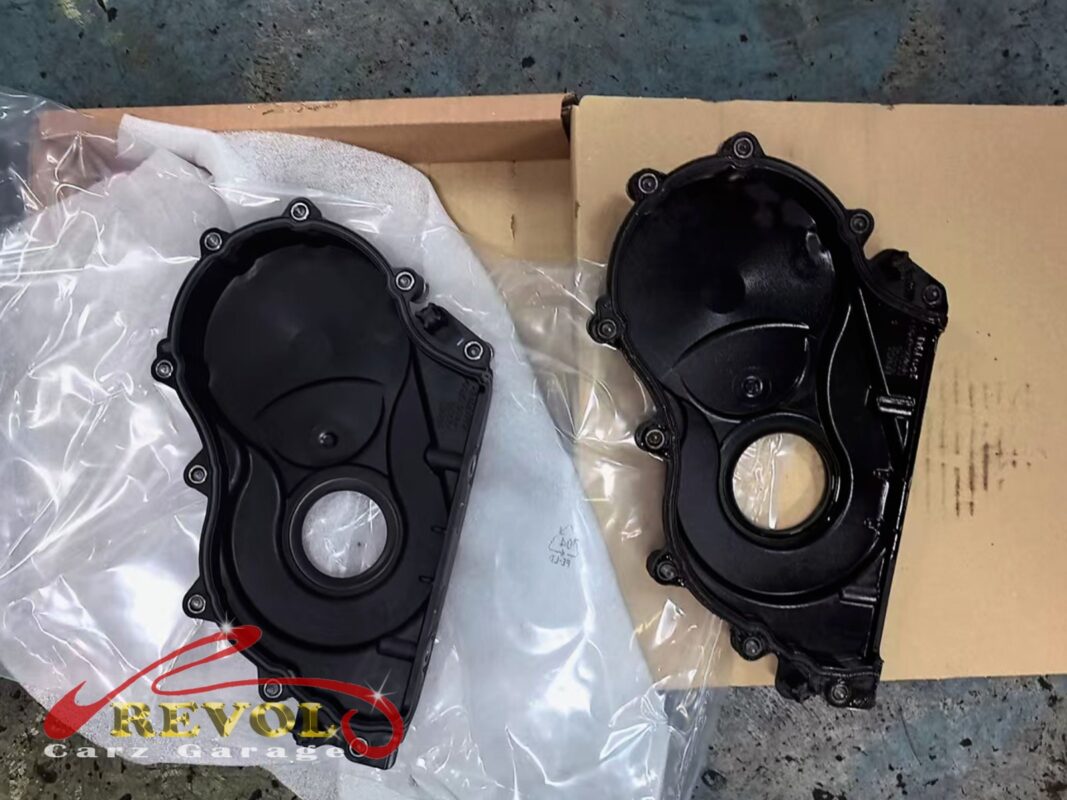 The old timing cover (right) beside the new BMW-spec replacement (left).