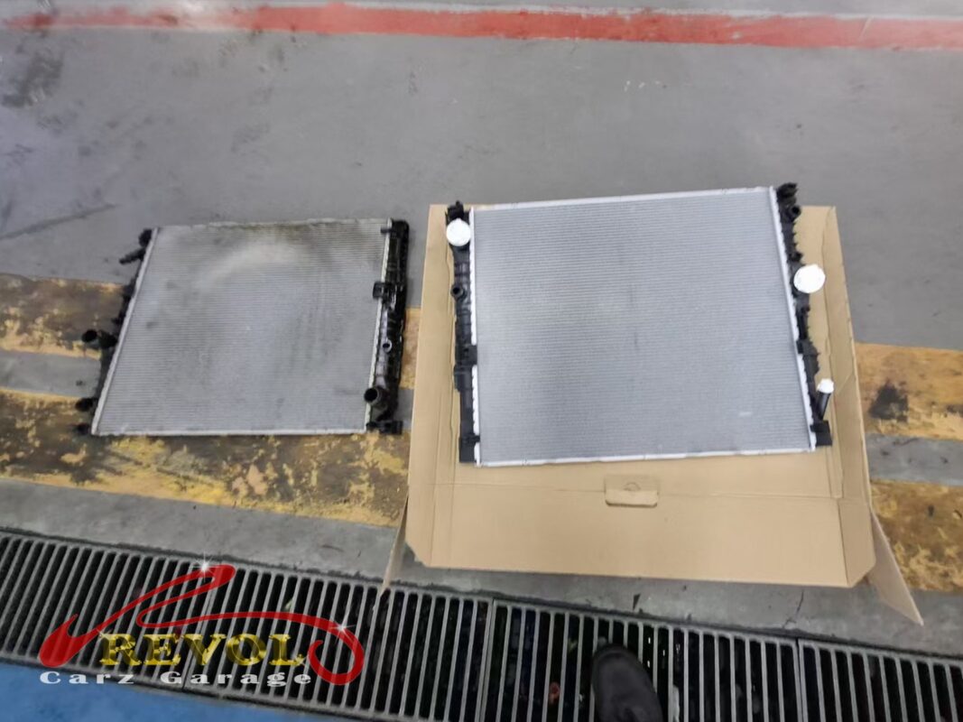 The old radiator (left, grimy) beside the new BMW-spec replacement (right).