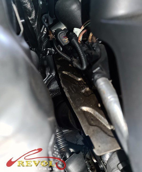 The warped plastic valve cover on the BMW 520i leaking oil.