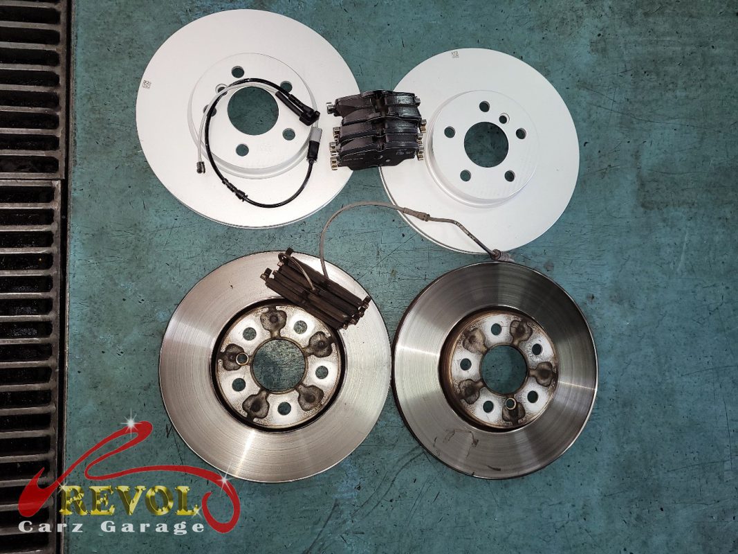 The old front discs removed alongside the new genuine set.