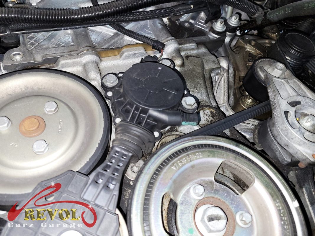 The old tensioner and idler pulleys removed alongside the belt.