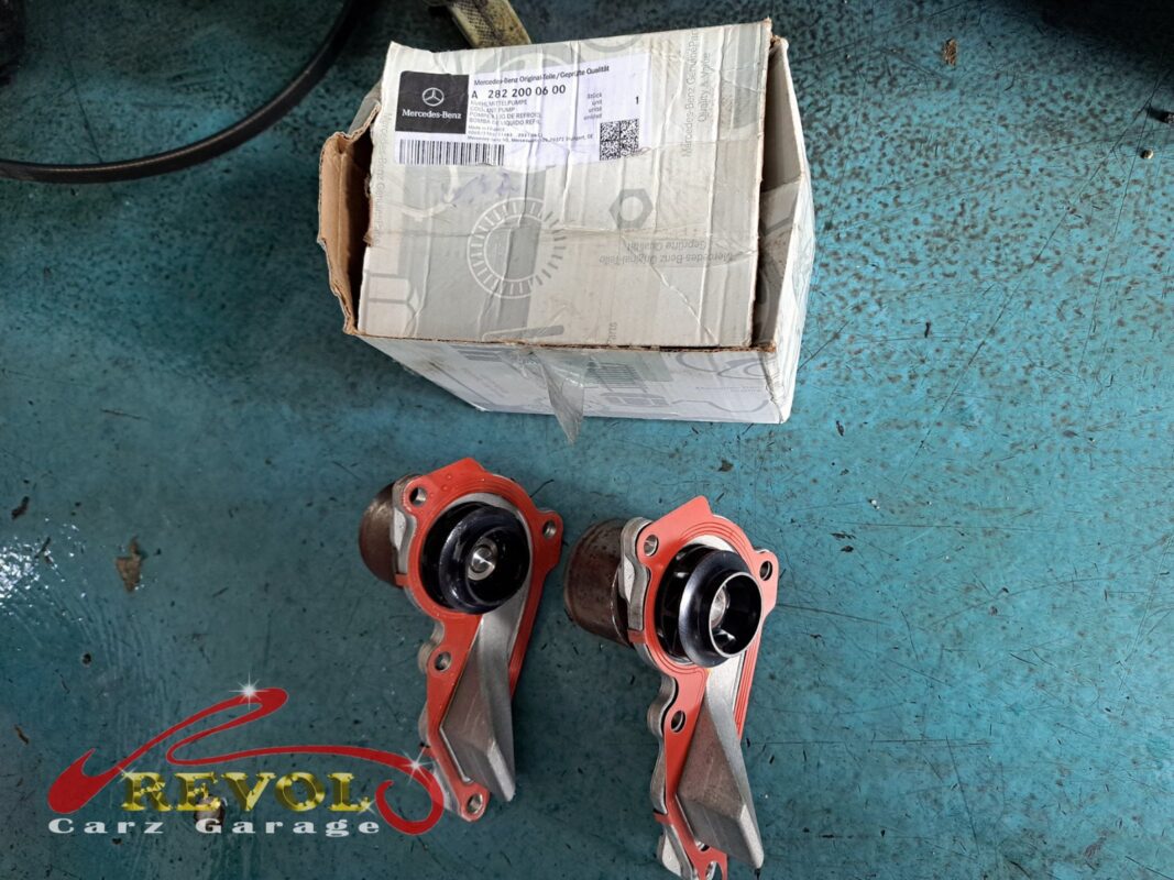 The old coolant pump removed beside the new Mercedes-spec replacement and thermostat, with fresh seals.