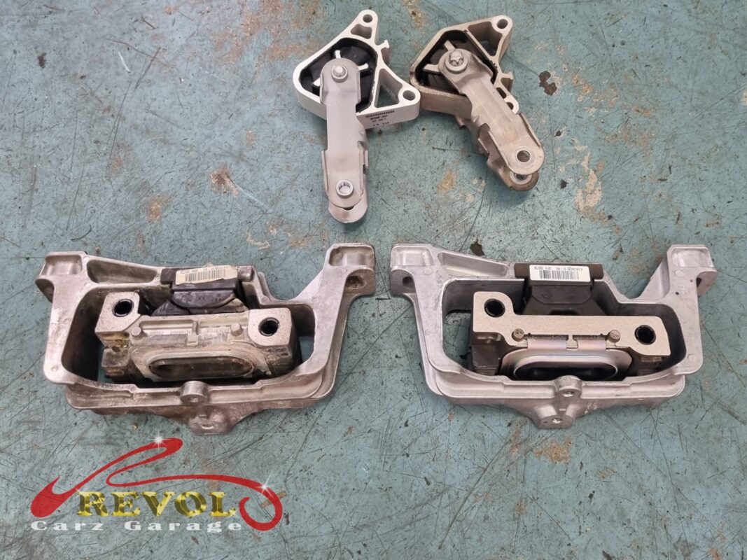 Two of the old mounts off the car, the rubber sunk in their cradles, with the torque-support arms above.