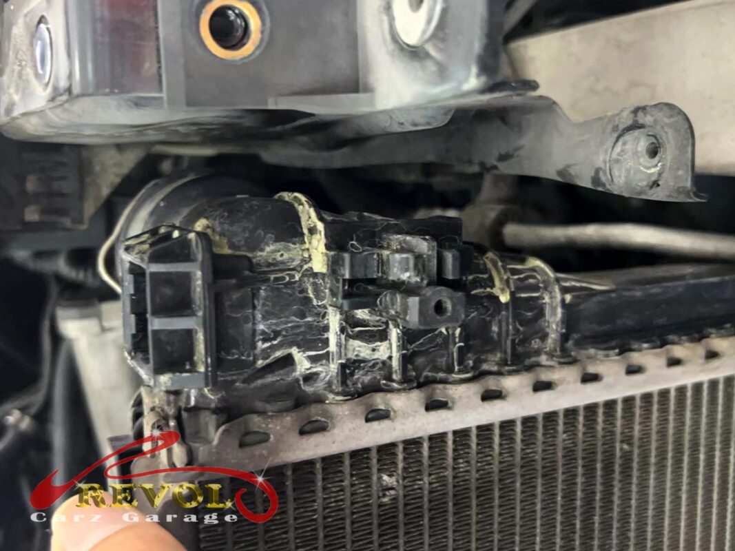 Crusty coolant residue baked along the radiator's plastic-to-core seam, the hairline crack made visible.