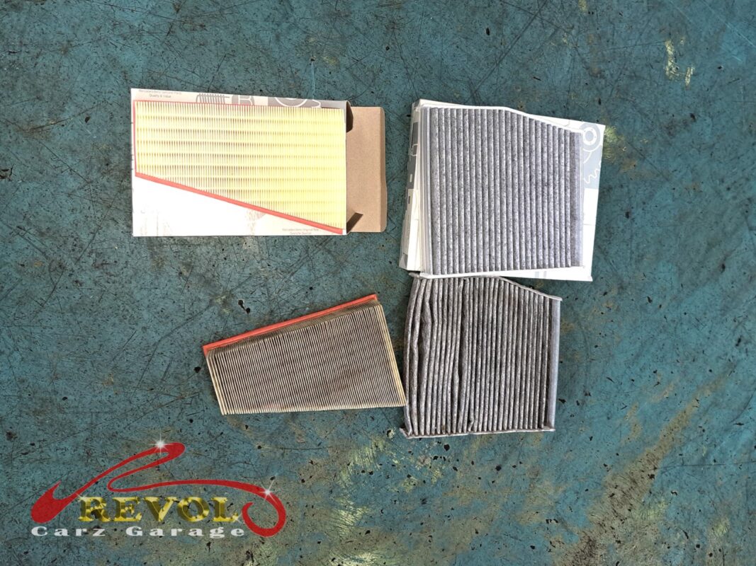 The clogged old engine air and cabin filters beside the new Mercedes-spec replacements.