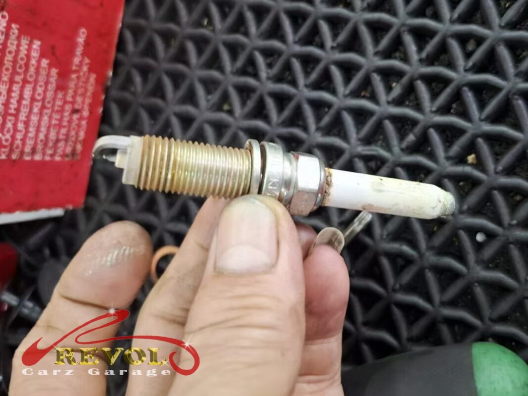 One of the old spark plugs out, the threads crusted and the white tip fouled after a long stint in service.