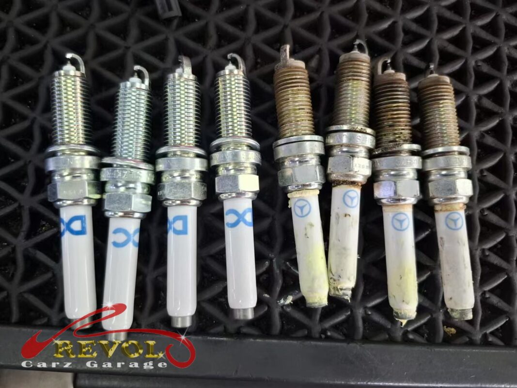 The four new Mercedes-spec plugs (left) beside the four removed (right), electrodes worn and tips fouled.