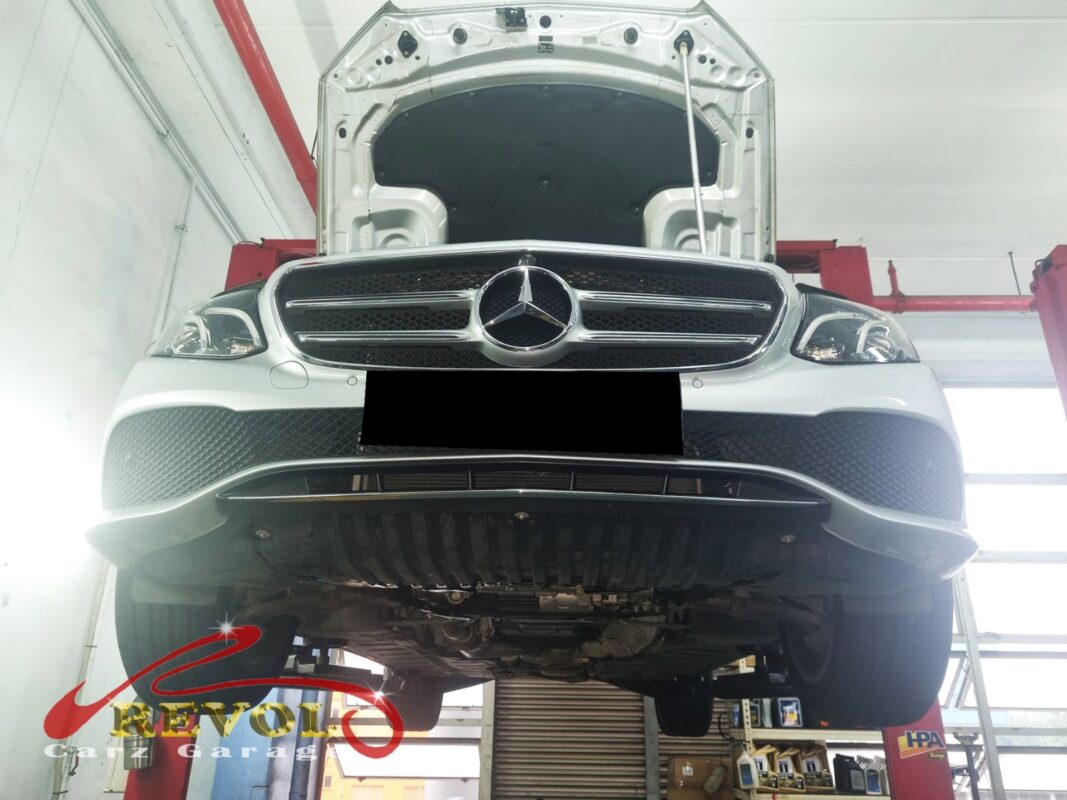 The E250 up on the two-post lift, hood open, in for the high running temperature.