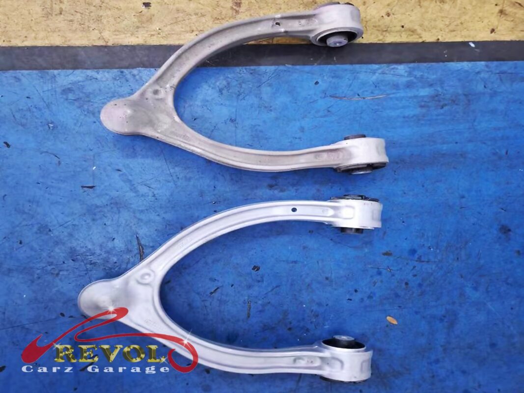 An old upper control arm (top) next to its new replacement (bottom) before the swap.