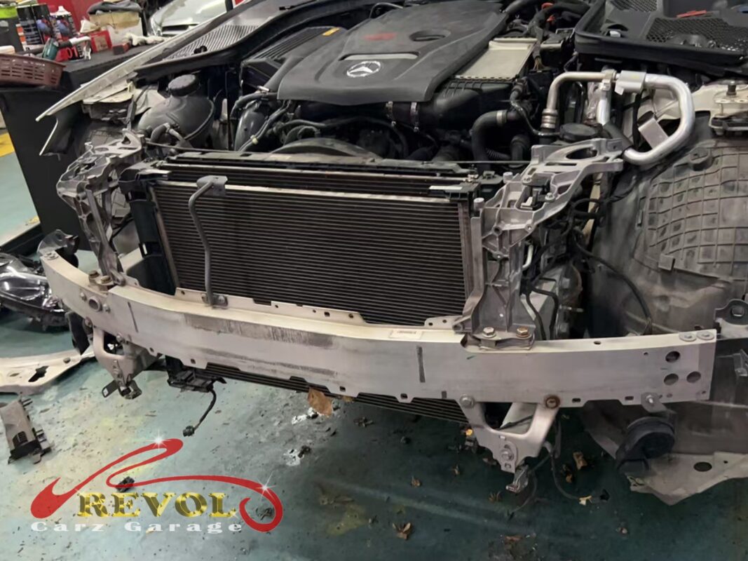 The front bumper off, the radiator and condenser stack at the front of the car exposed for access.