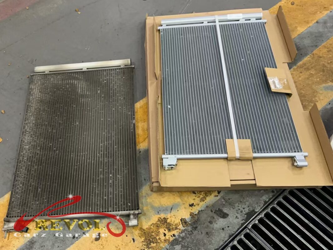 The old AC condenser (left, fins grimed dark) beside the new Mercedes-spec replacement (right), fresh from the box.