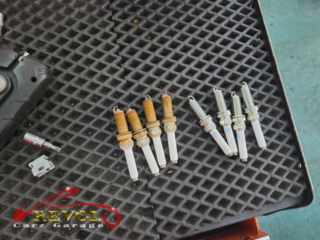 The four old spark plugs (left, threads crusted) beside the four new Mercedes-spec replacements (right).