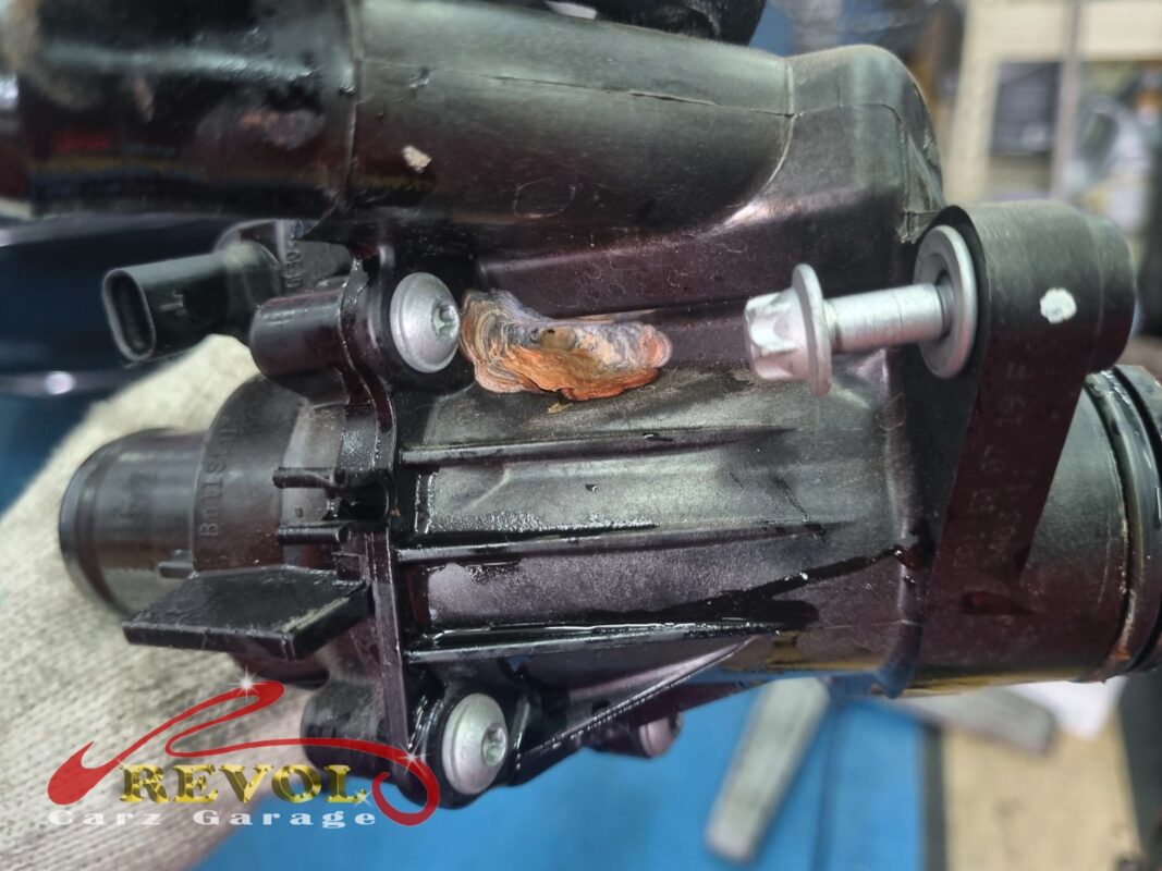 The old thermostat housing out, coolant crusted around the seal where it had been weeping.