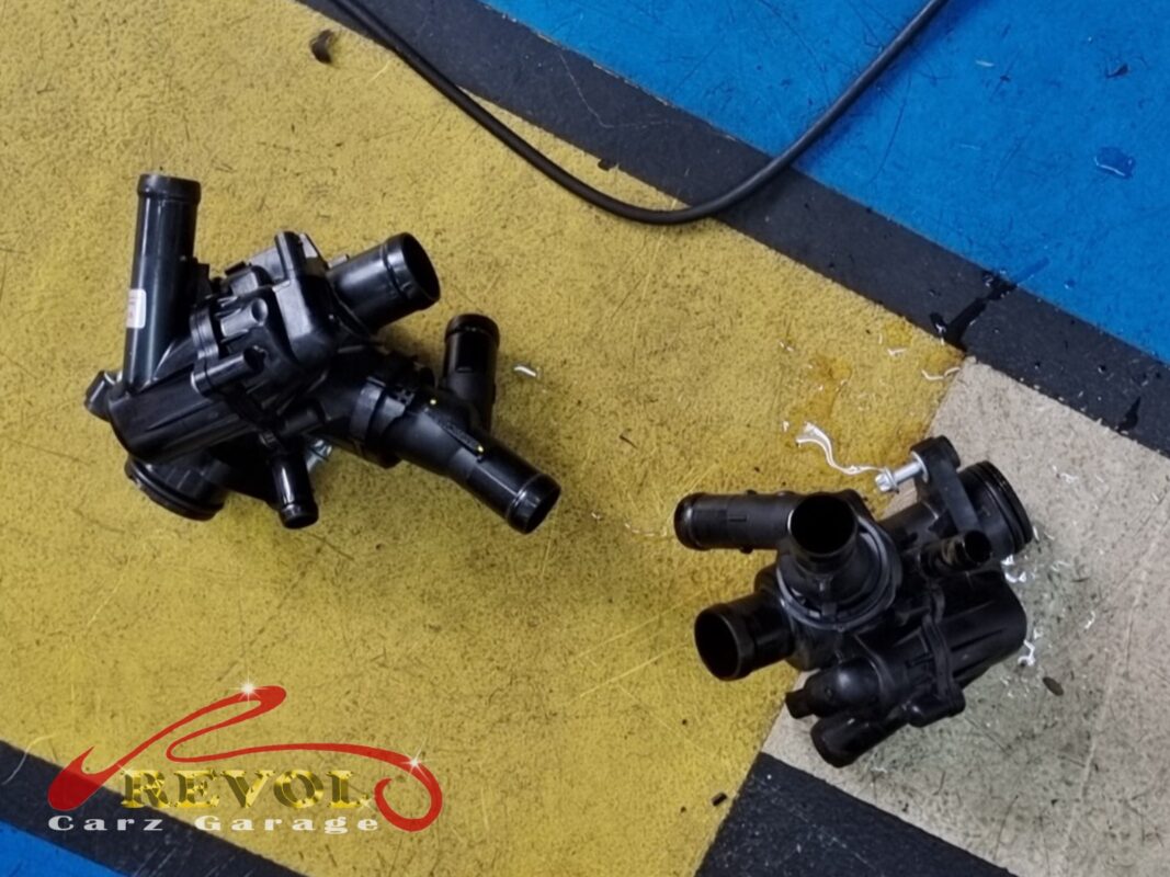 The old thermostat housing module beside the new Mercedes-spec replacement.