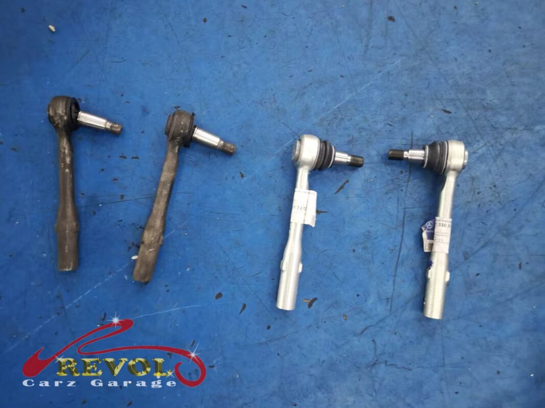 The two old outer tie rod ends (left, boots split) beside the new Mercedes-spec pair (right).