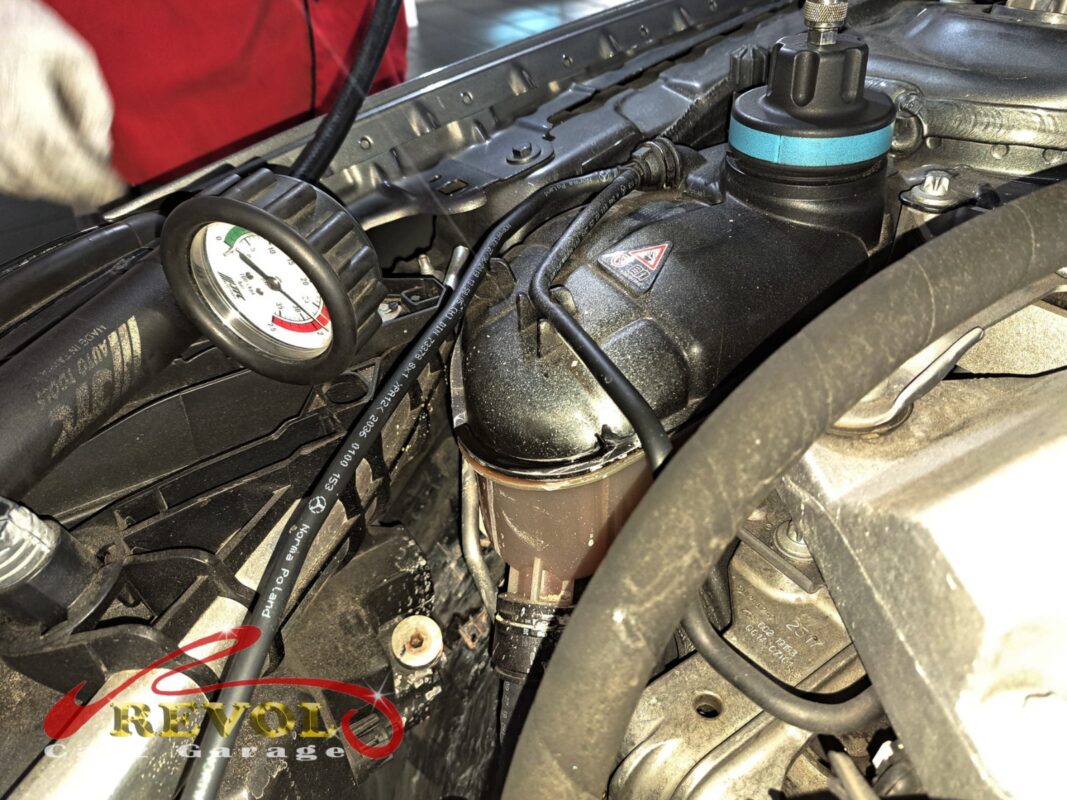 A cooling-system pressure tester on the GLA180's expansion tank during the leak hunt.