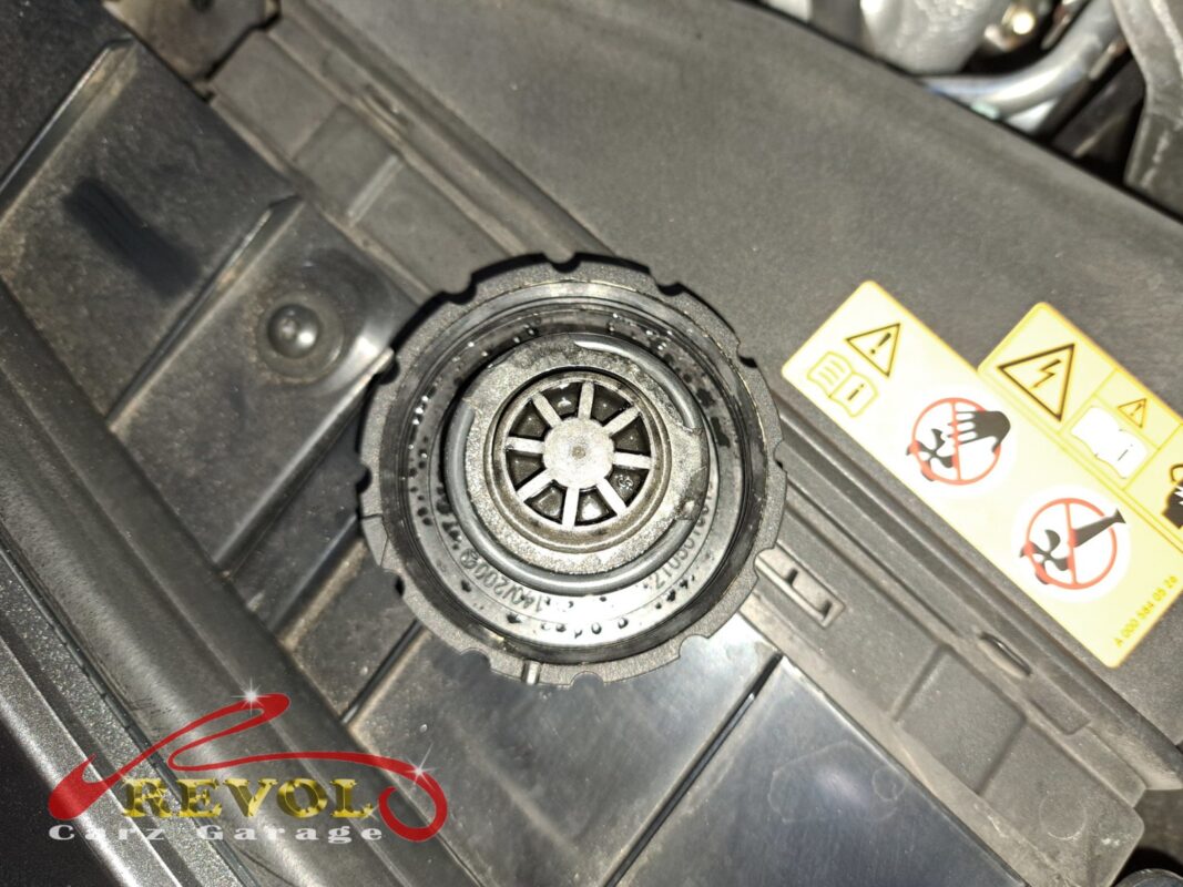 The expansion tank's filler neck, cap off, coolant residue crusting around the rim.