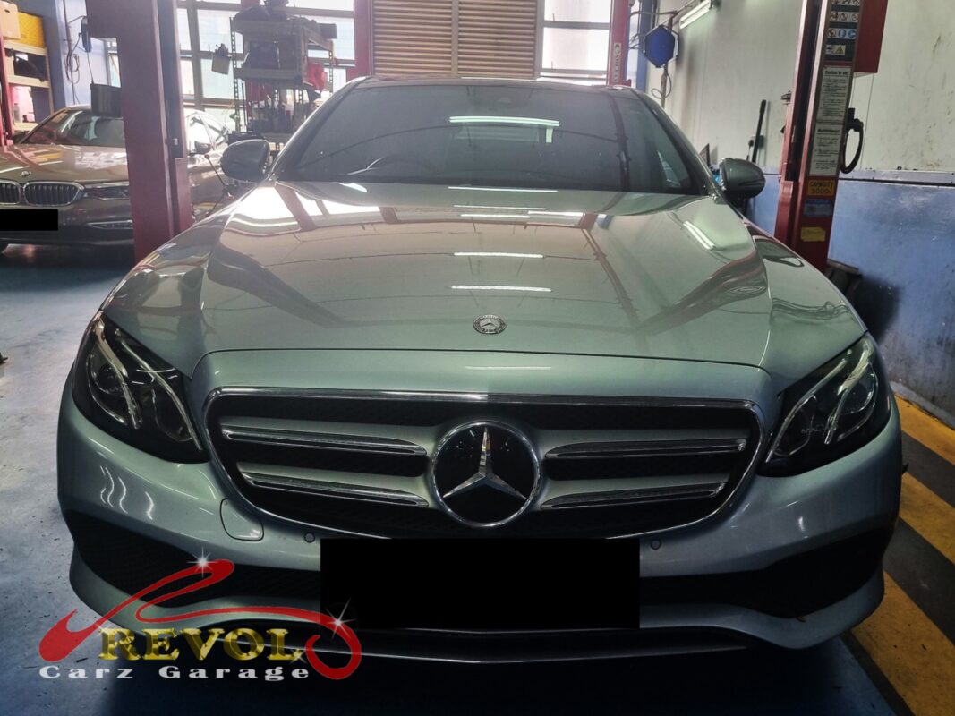 Mercedes-Benz E200 on the workshop lift for fan belt set replacement.