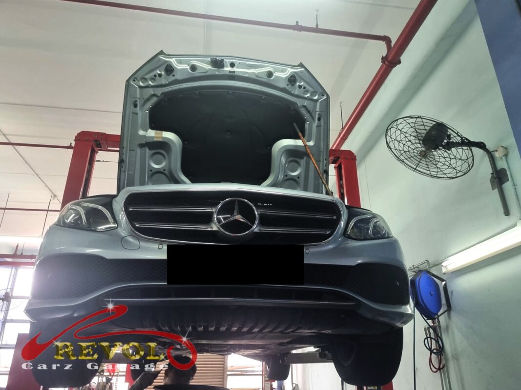 The E200 up on the two-post lift, hood open, in for the belt squeal.