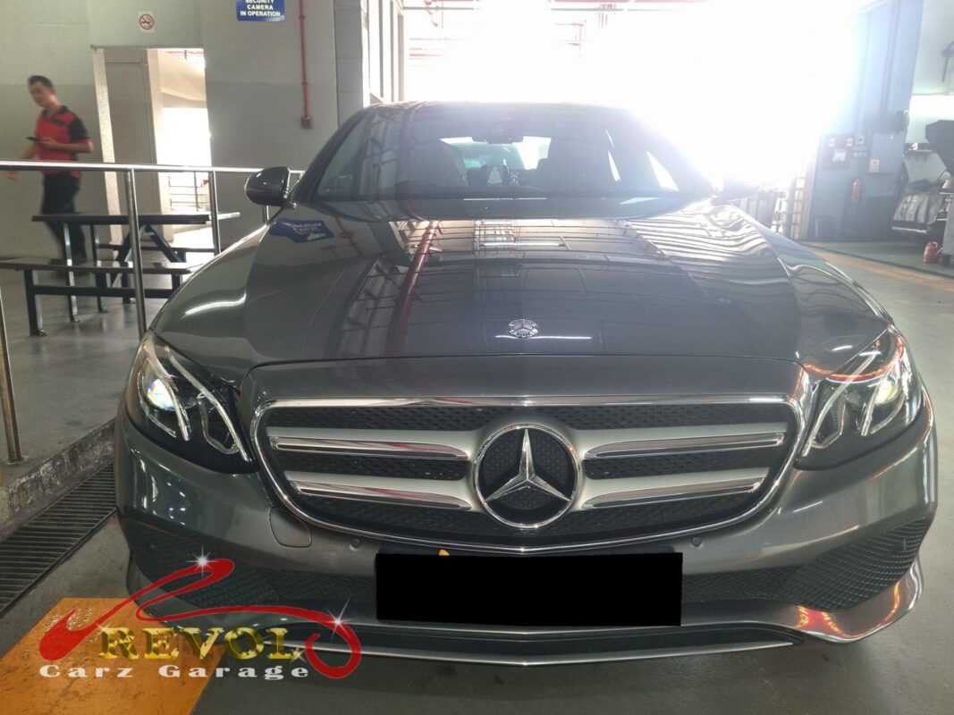 Mercedes-Benz E200 on the workshop lift with both front wheels off for control arm replacement.