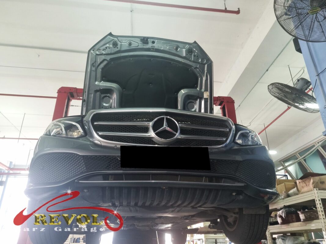The E200 up on the two-post lift, hood open, in for the loose steering.