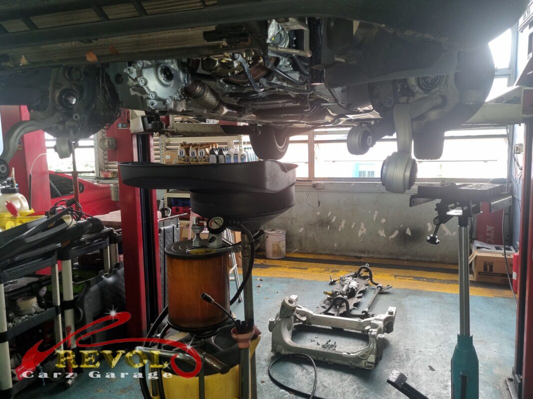 The GLC300 up on the lift, the front subframe dropped to reach the oil pump, the old oil draining out.