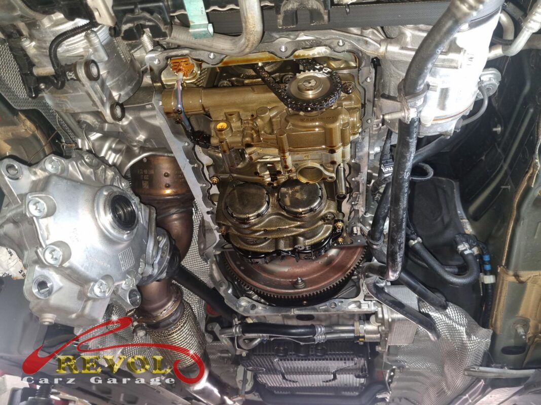 Looking up into the engine with the oil pan off, the chain-driven oil pump and its control valve exposed.