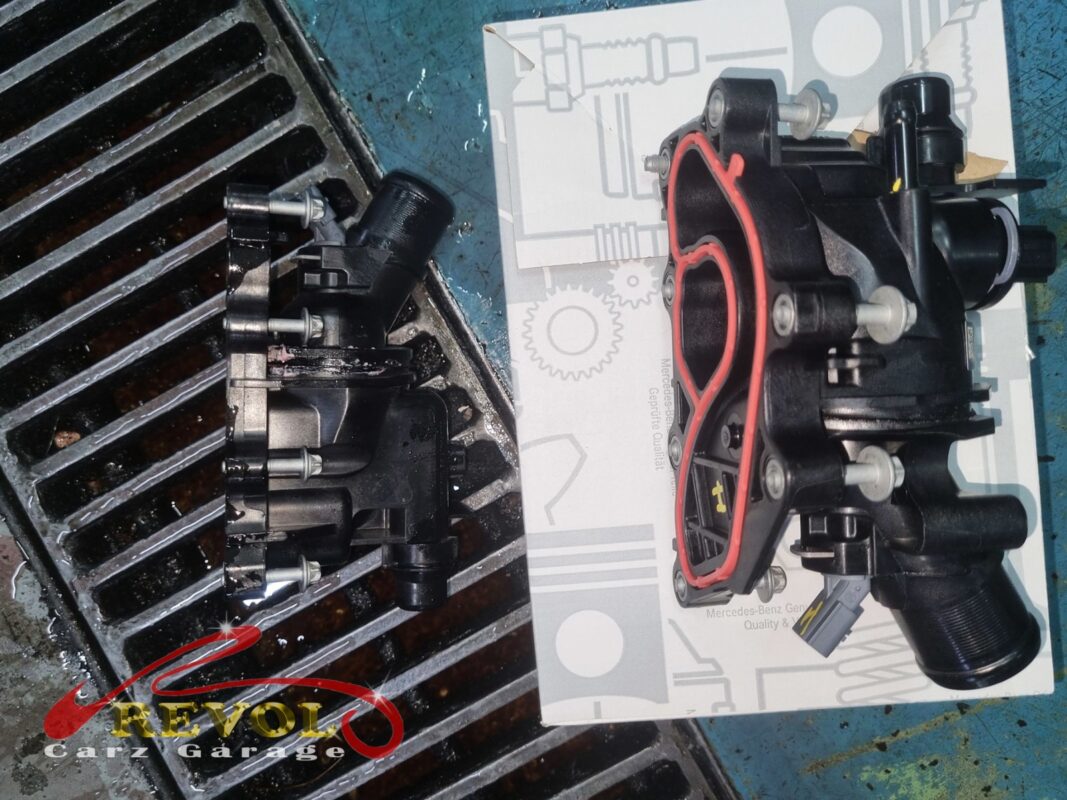 The old thermostat housing (left) beside the new Mercedes-spec module (right) with its fresh red seal.