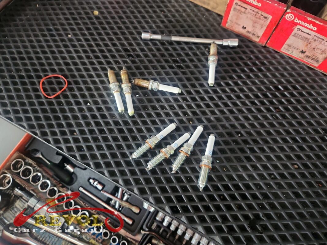 The old spark plugs (top, threads crusted) beside the new Mercedes-spec set (bottom), changed with the injectors.