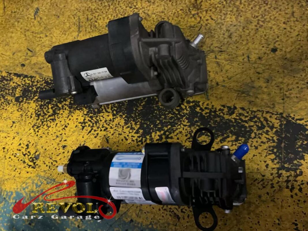 The old AIRMATIC air compressor (top, grimy) beside the new replacement (bottom), done with the struts.
