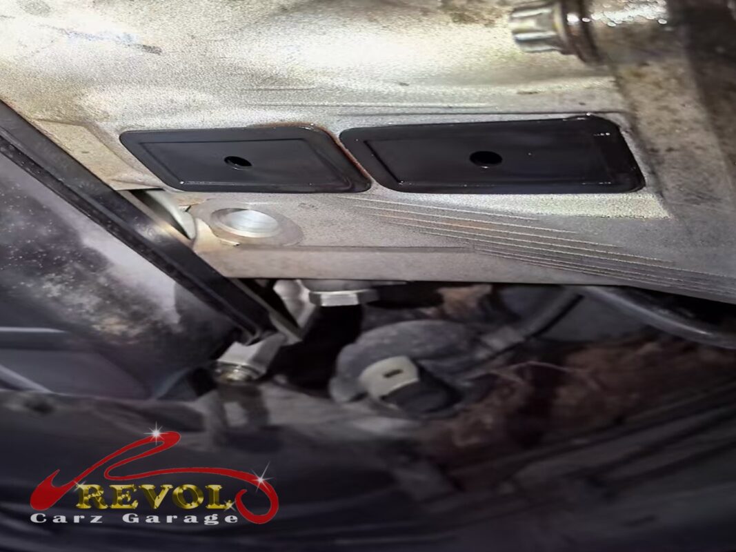 The bellhousing area under the car, oil staining tracking down from the back of the engine.