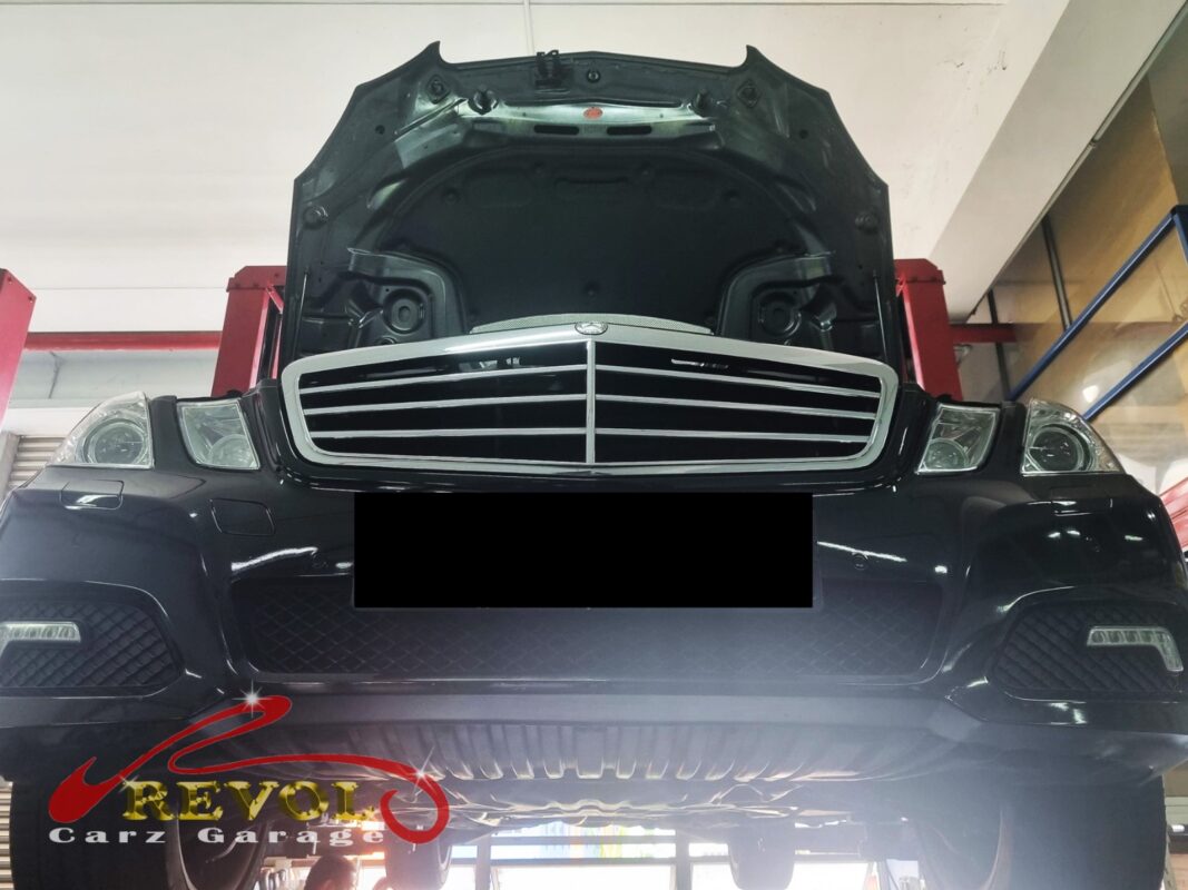 The E250 up on the two-post lift, hood open, in for the fuel smell.
