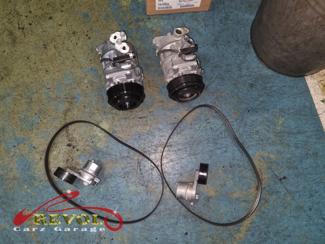 The old AC compressor beside the new Mercedes-spec replacement, with the new serpentine belt and tensioner below.